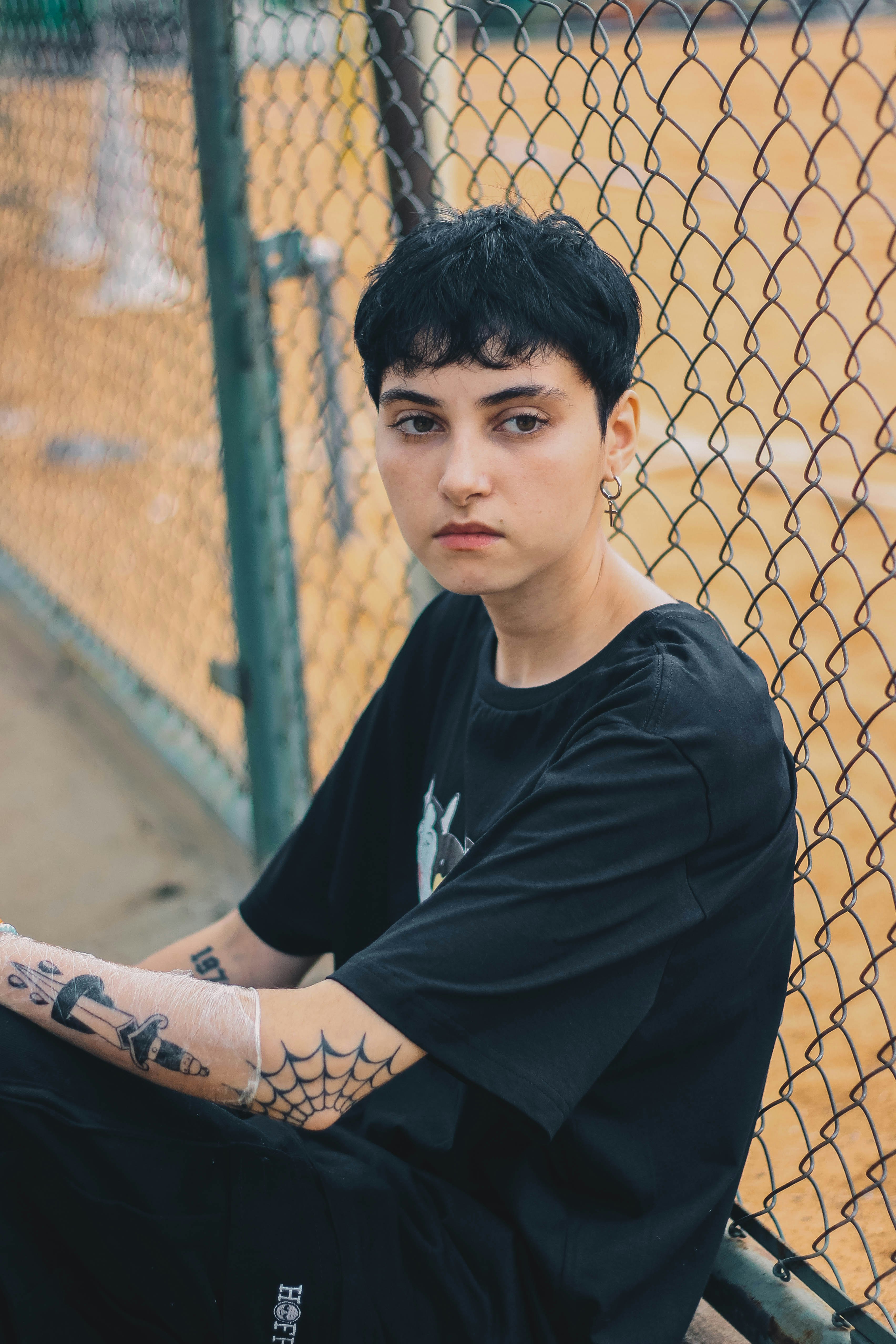 man in black crew neck t-shirt leaning on brown metal fence during daytime